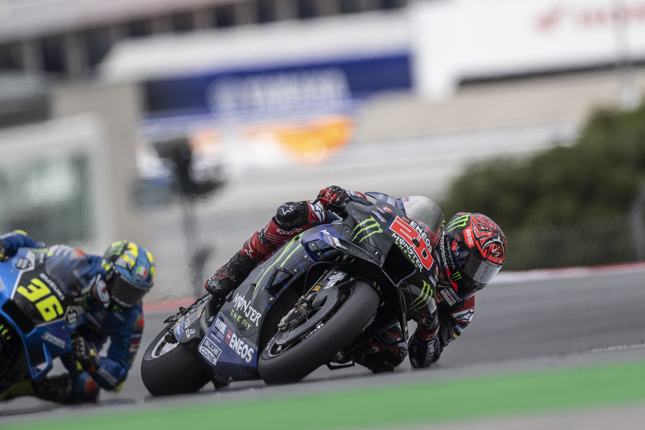 Racers making a tight turn on MotoGP track