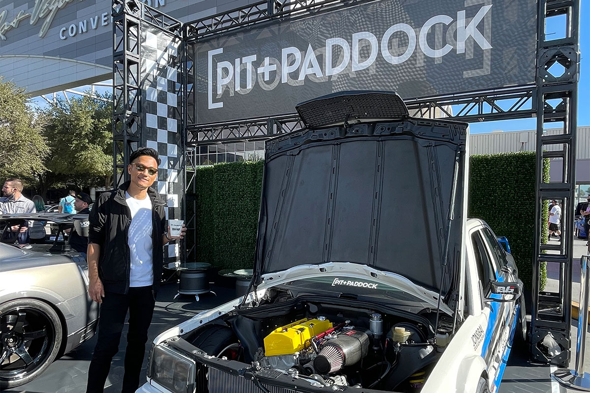 Dai Standing By Pit Paddock Sign and Car