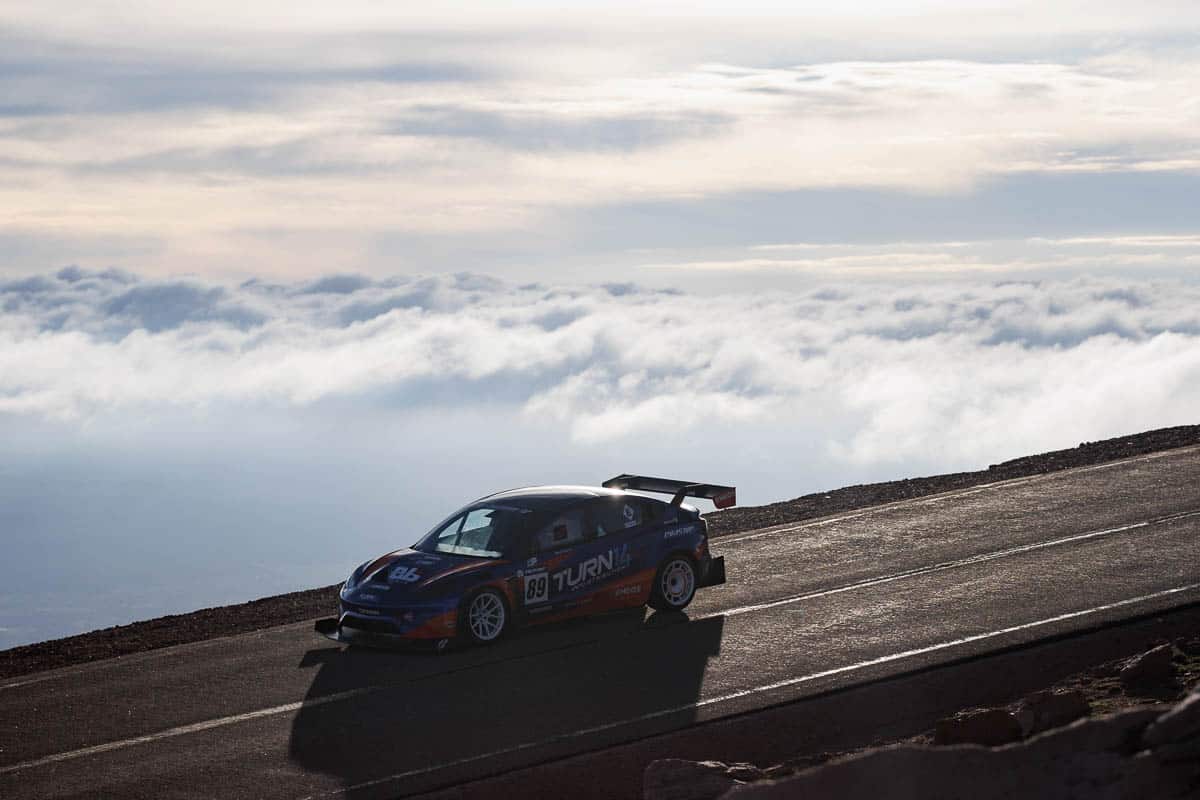 Pikes Peak car on street with clouds behind it