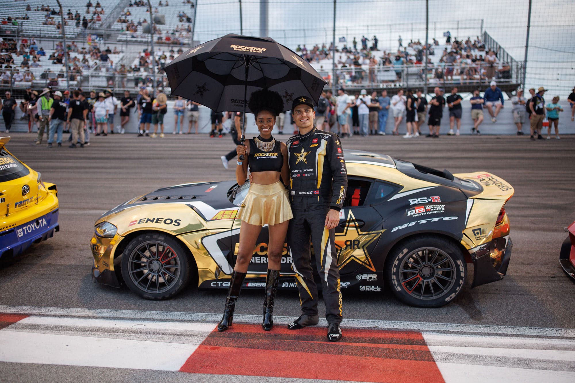 Racer posing with girl in front of car