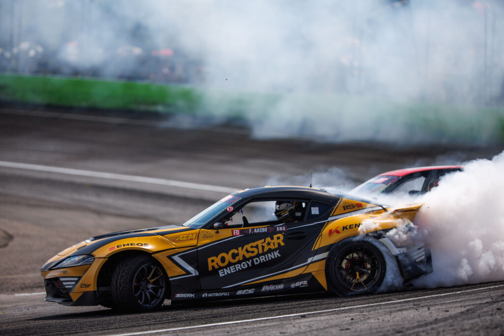 two race cars on a track with smoke coming out of the front